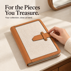 A hand resting on the leather strap of a closed canvas jewelry book on a dressing table.