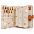 Open FOOIKOS jewelry organizer book with necklaces on leather loops and earrings and rings in clear zip pockets.
